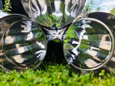 Selective focus view at a lot of reflective chrome metal tubes on a grass surface