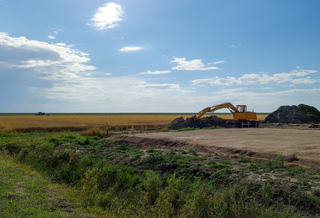 Flensburg, Germany - 13. August 2021: Big yellow excavator on an agriculural fieldのeditorial素材