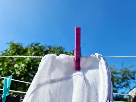 Clothes hung out on a sunny day to dry on a washing line and fastened by the clothes pegs.