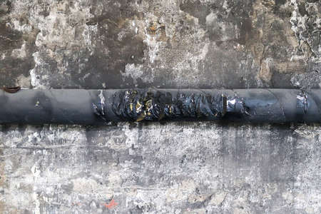 Wall in a steel mill with clear signs of use, cracks and pipes. High resolution backgroundの写真素材