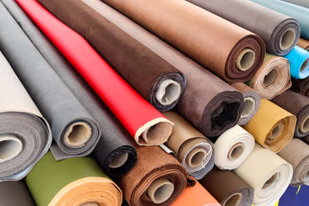 Close up view on rolled samples of cloth and fabrics in different colors found at a fabrics market.の写真素材