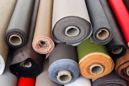 Close up view on rolled samples of cloth and fabrics in different colors found at a fabrics market.の写真素材