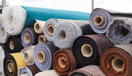 Close up view on rolled samples of cloth and fabrics in different colors found at a fabrics market.の写真素材