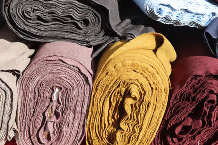 Close up view on rolled samples of cloth and fabrics in different colors found at a fabrics market.の写真素材
