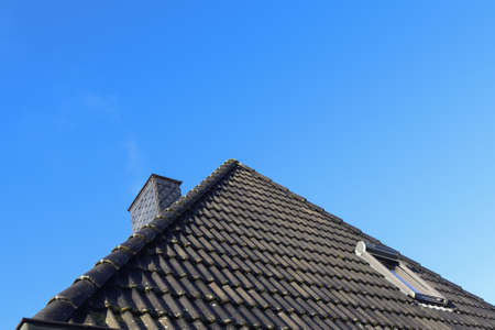 Open roof window in velux style with black roof tiles