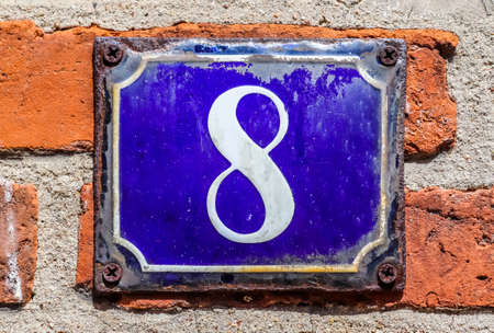 Old brick wall. Texture of old weathered brick wall with a number 8 on a blue sign