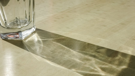 Drinking glass with caustic light effects on a wooden tableの写真素材