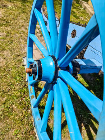 An old wooden wagon wheel in blue paintの写真素材
