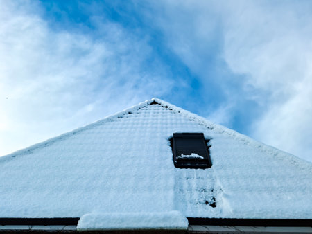Open roof window in velux style with black roof tiles covered in snowの写真素材