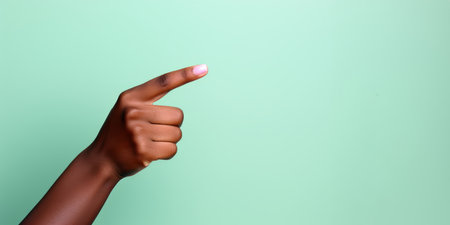 A womans hand pointing to the top in front of a pastel colored backgroundの素材