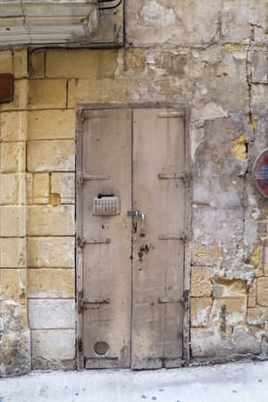 An old light brown door to a flat in the alleyways of Maltas historic old townsの写真素材