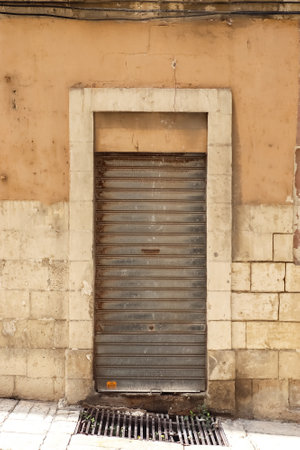 The textured surface of an old flat door in the serene alleys of Maltaの写真素材