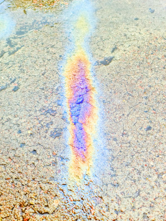 Oil slick in bright colours on the asphalt of an old roadの写真素材