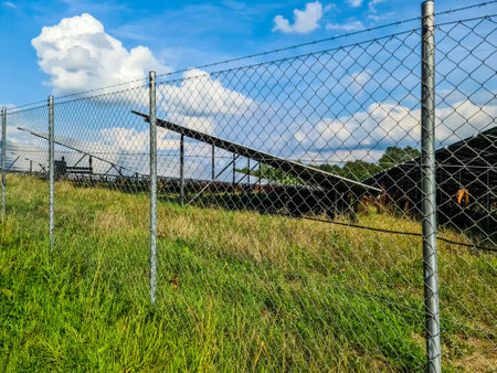 Chain link fence protecting solar panels in a field, renewable energy production and securityの写真素材