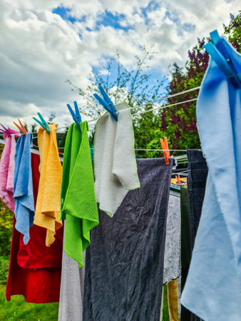 Freshly washed laundry drying on a clothesline in a garden under a cloudy skyの写真素材