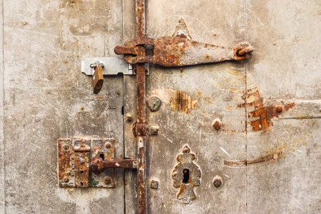 Rusty metal door with latch and padlock closing, creating a sense of security and privacyの写真素材
