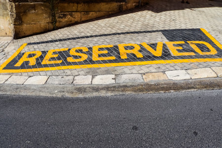 Yellow reserved sign painted on a paved street indicating a reserved parking spaceの写真素材