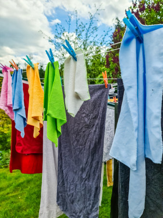 Colorful towels and clothes hanging on a clothesline and drying in the wind in a gardenの写真素材