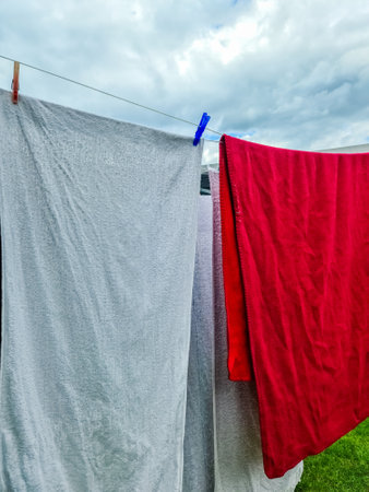 Clean laundry, including towels and blankets, hanging on a clothesline and drying under a cloudy skyの写真素材