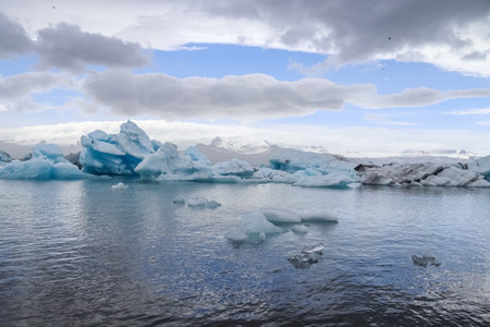 Icebergs are floating in jokulsarlon glacier lagoon in iceland, creating a breathtaking view under a...
