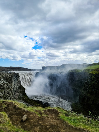 Powerful waterfall in iceland surrounded by rocky cliffs and lush greenery