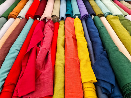 Many colorful fabrics hanging in a textile shop, displaying a variety of colors and textures, perfect for sewing and crafting projectsの写真素材