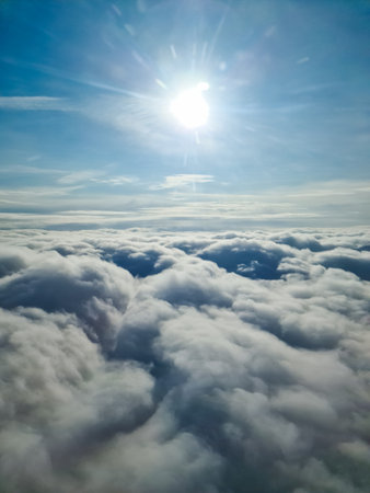 Aerial view of a beautiful cloudscape with the sun shining brightly above, seen from an airplane windowの写真素材