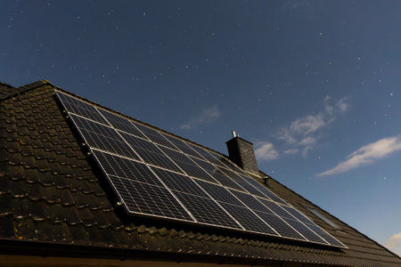 Photovoltaic panels installed on the roof of a house producing sustainable energy at night under a...
