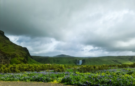 Breathtaking icelandic landscape featuring a waterfall cascading down lush green hills under a...