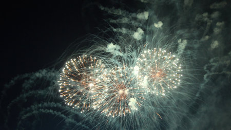 Golden fireworks exploding against a dark sky, illuminating the night with a vibrant display of...