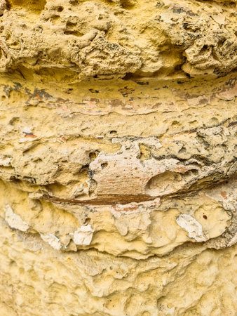 Detailed view of a weathered yellow rock surface revealing erosion patterns, textures, and color variationsの写真素材