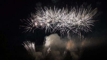 Bright fireworks bursting in the night sky, creating colorful displays of light and smoke during a...