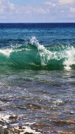 Ocean wave crashing with white foam and splashes in clear turquoise sea, vibrant tropical surf off a...