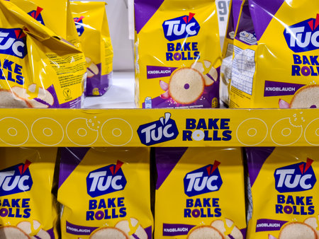 Kiel, Germany - 24. November 2025: TUC Bake Rolls garlic flavor packaged snacks displayed on a grocery store shelf, showing multiple yellow and purple bagsのeditorial素材