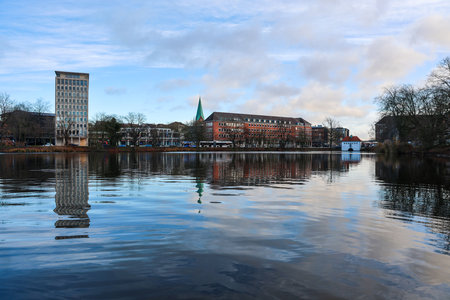 Kiel, Germany - 13. December 2025: Urban buildings reflecting in calm water under a cloudy sky in Kiel, Germanyのeditorial素材