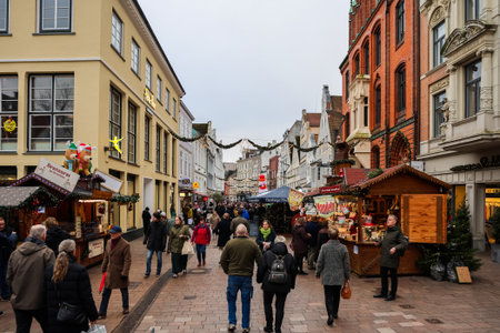 Flensburg, Germany - 21. December 2025: Shoppers walking bustling market street with traditional...