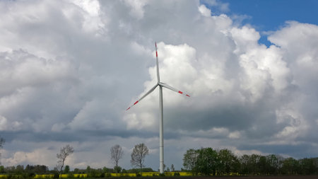 Wind turbine stands in a rural field under a cloudy sky, representing sustainable energy production