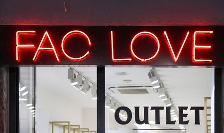 Naples, Italy - 5. March 2026: Red neon letters forming FAC LOVE illuminate a store window with...