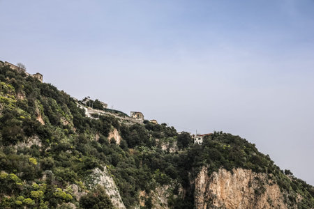 Homes are built high on a steep, vegetated cliffside along the Amalfi Coast