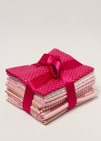 Stack of pink shades folded fabrics with gift ribbon from aboveの写真素材