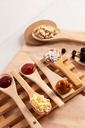 Wooden spoons on a wooden table on beige tablecloth with natural ingredients such as cheese,...