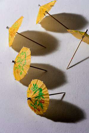 Yellow summer cocktail paper umbrellas on white plastic tableの写真素材