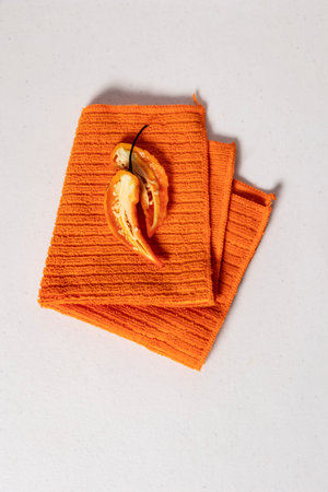 Orange bell pepper cut in half with seeds in the middle on orange textured kitchen towel folded