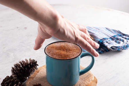 man hand grabbing blue cup with hot drink from above