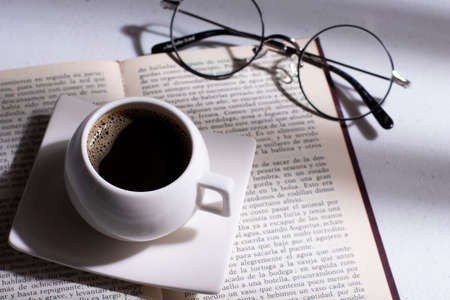 white cup with Colombian coffee on a book and round glassesの写真素材
