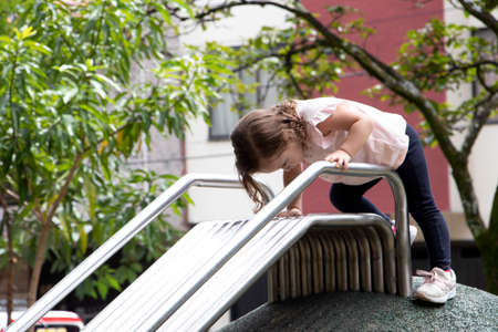 Little girl in pink shirt and jean playing in cement and metal parkの写真素材
