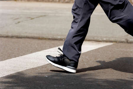 Legs of man in black pants and black shoes exercising on the street