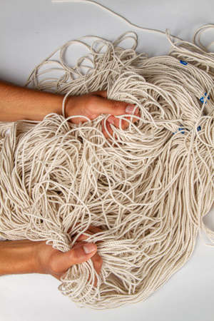 Man's hands tightly grasping tangled macrame threads