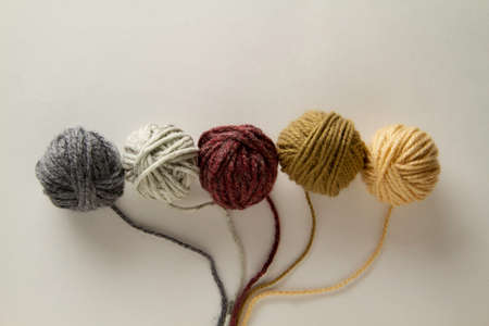 Balls of colored wool in a row and a strand of yarn is attached