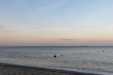 Calm Atlantic Ocean at sunrise with buoys and boats in the distance